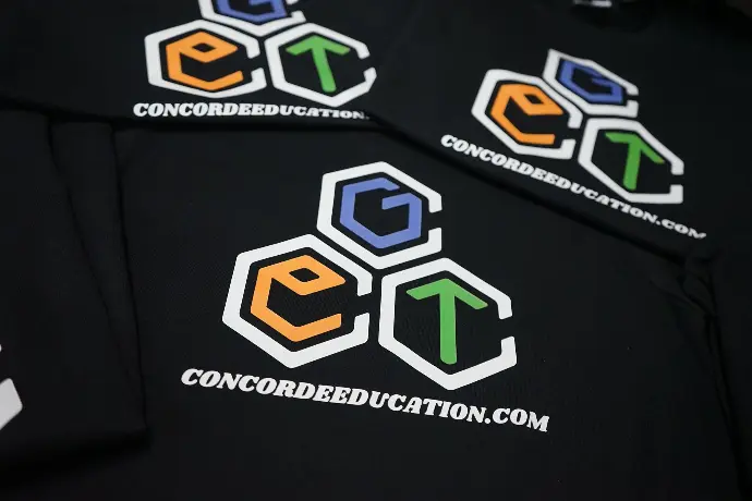 Close-up of custom-printed apparel for Concord Education, featuring a vivid, multi-colored logo. The design showcases the brand's identity through geometric shapes and the website URL, highlighting the organization's focus on innovative and accessible education solutions.